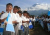 Jovenes guatemaltecos en un acto de patriotismo con la bandera de Guatemala y un volcan al fondo